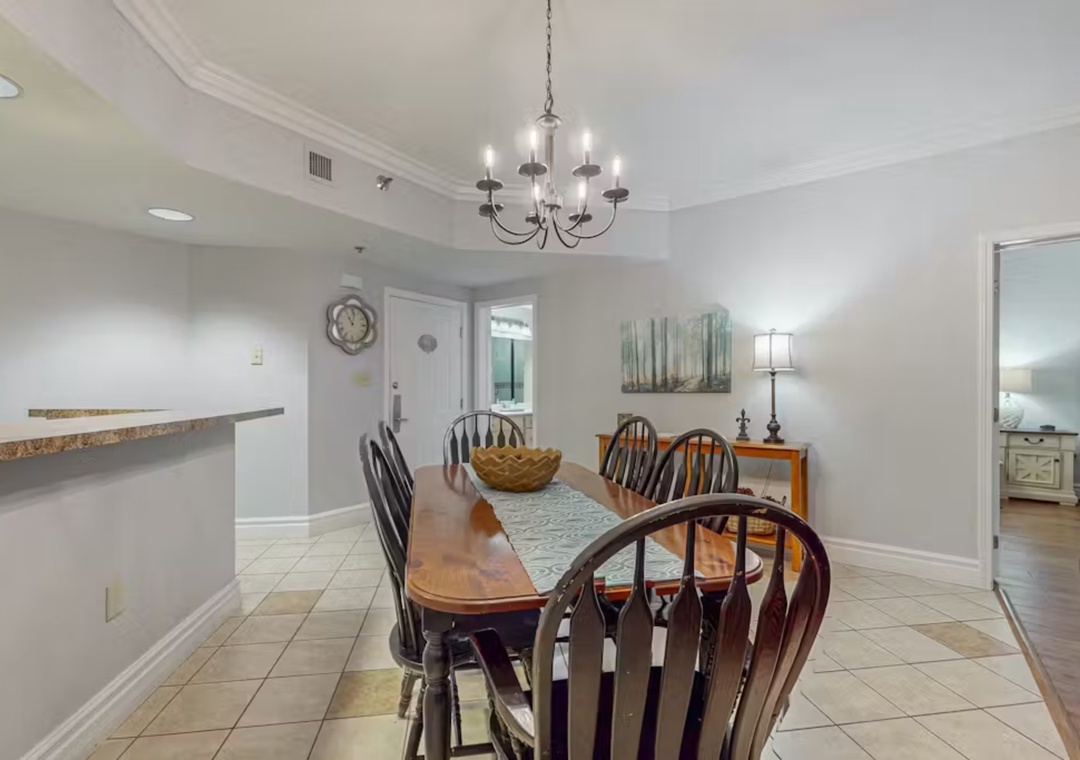Gather around this welcoming dining table where memorable conversations flow beneath elegant lighting and coastal artwork.
