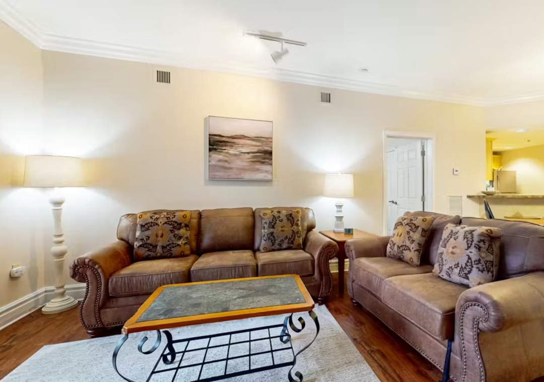 Sink into plush leather sofas in your spacious living room, where warm lighting and elegant decor create the perfect retreat for relaxation.