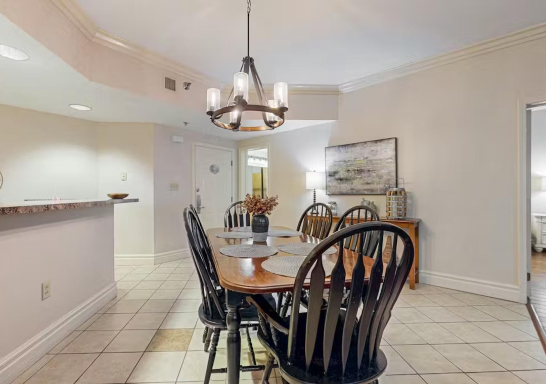 Gather around this elegant dining table where every meal becomes a memorable occasion, bathed in warm light from the stylish chandelier above.