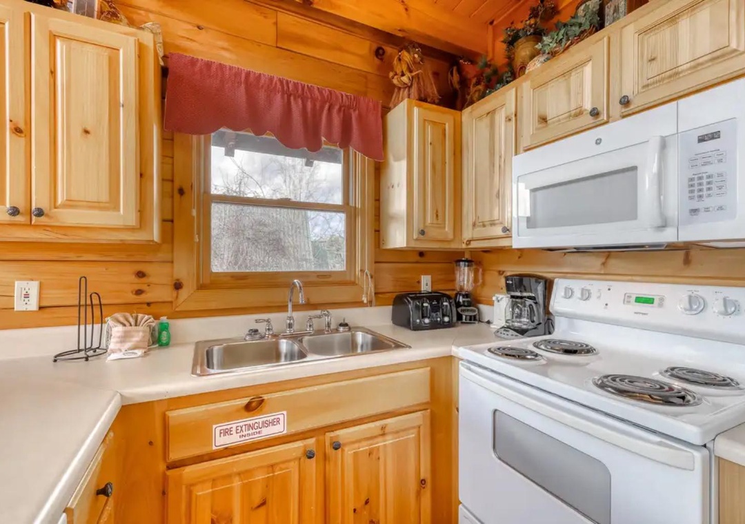 Your fully equipped kitchen features warm knotty pine cabinets, modern appliances, and a window overlooking peaceful wooded surroundings. Everything you need to prepare meals and enjoy a home-away-from-home experience.