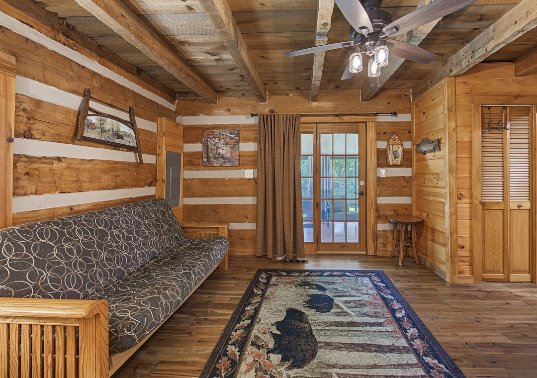 Rustic wood-beamed cabin with vaulted ceilings and futon seating invites you to unwind in cozy, mountain-inspired comfort with charming details throughout.