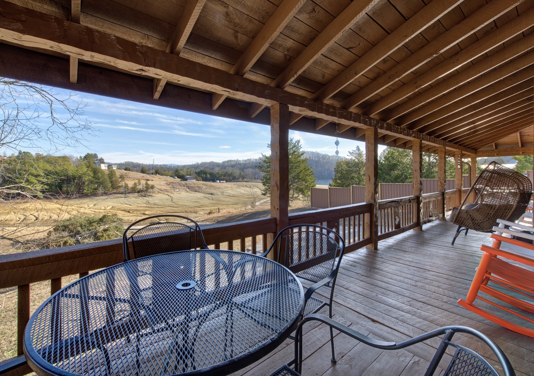 Sip your morning coffee while gazing across rolling hills from this spacious covered deck with comfortable outdoor seating.