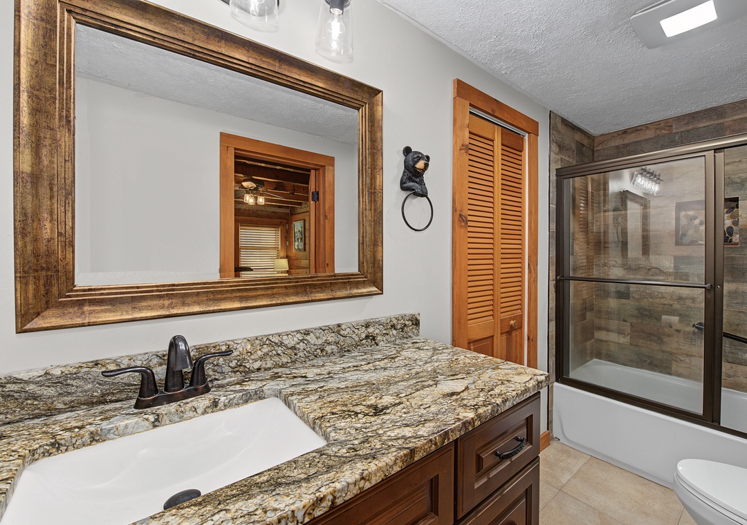 Freshen up in your elegantly appointed bathroom, featuring rich granite countertops, warm wood accents, a large soaking tub, and a separate glass-enclosed shower for ultimate comfort and relaxation.