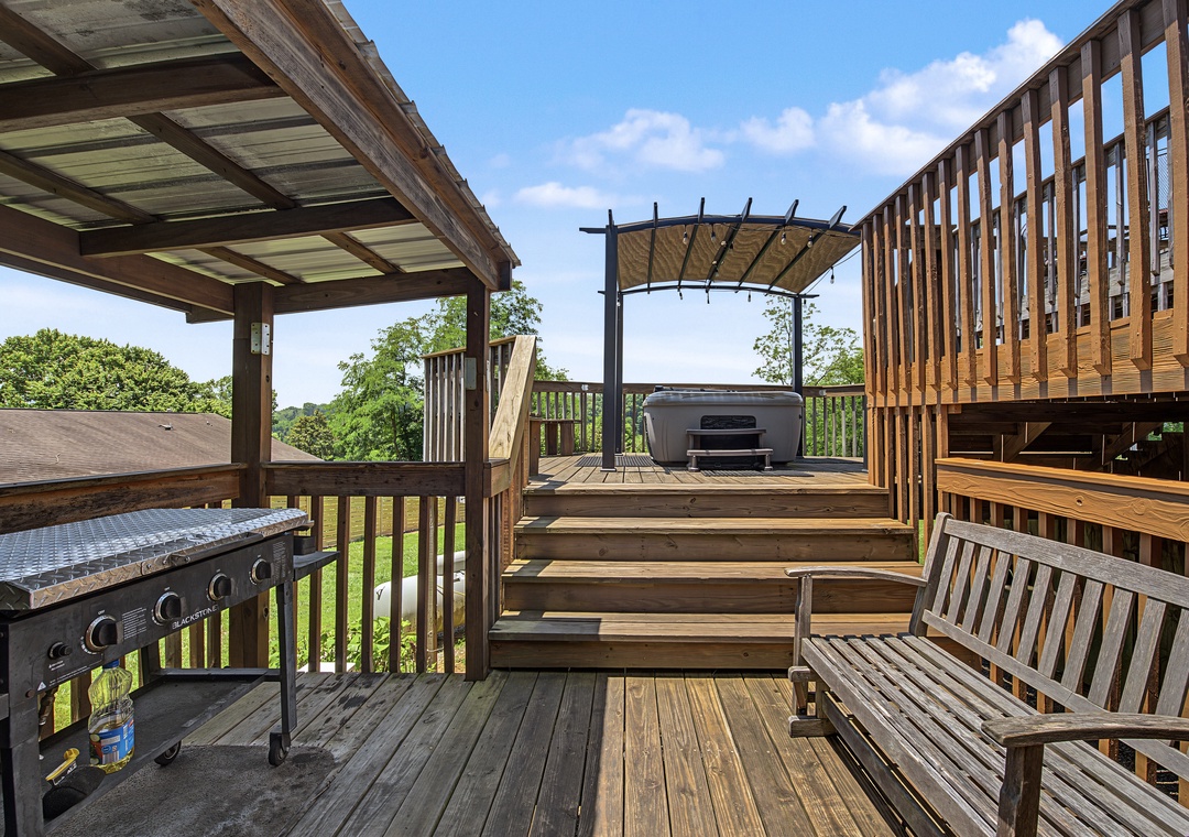 This expansive multi-level deck features a hot tub, built-in BBQ, and shaded pergola areas overlooking lush greenery—your ideal outdoor escape for relaxation and grilling.