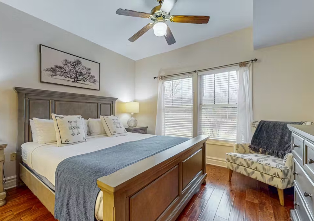 Rest peacefully in your cozy bedroom featuring a plush king bed, warm wood floors, and gentle ceiling fan for ultimate comfort.