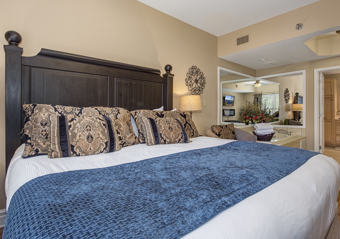 Sink into plush bedding with elegant patterned pillows in this sophisticated bedroom featuring beautiful ceiling details and stylish furnishings.