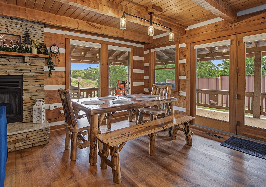 Gather around this handcrafted log dining table where your group can share meals and laughter. Rustic wood beams overhead, a stone fireplace, and expansive windows framing forest views create a warm, inviting mountain retreat.