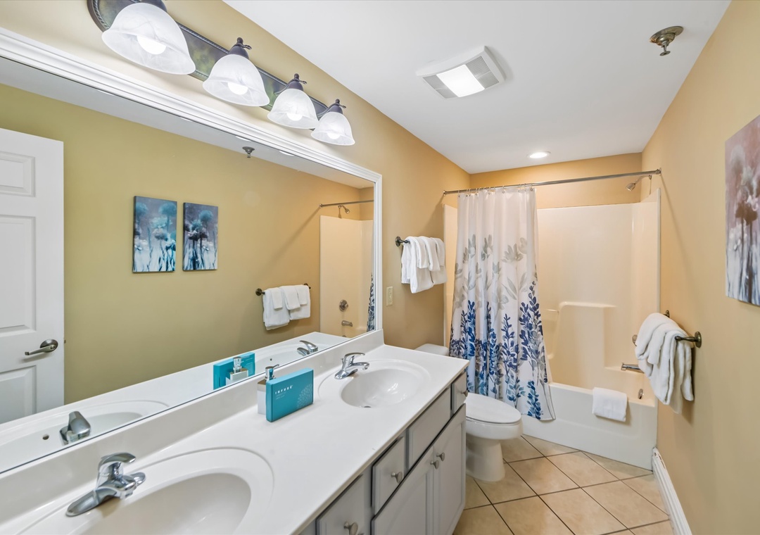 Refresh in your spacious bathroom with dual vanities, modern shower-tub combo, and warm lighting for your morning routine.
