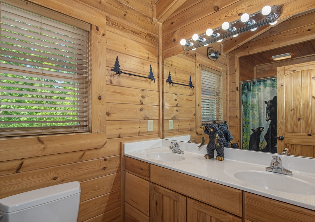 Step into your rustic bathroom featuring dual sinks, warm wood walls, and charming bear-themed touches that make you feel at home in nature.