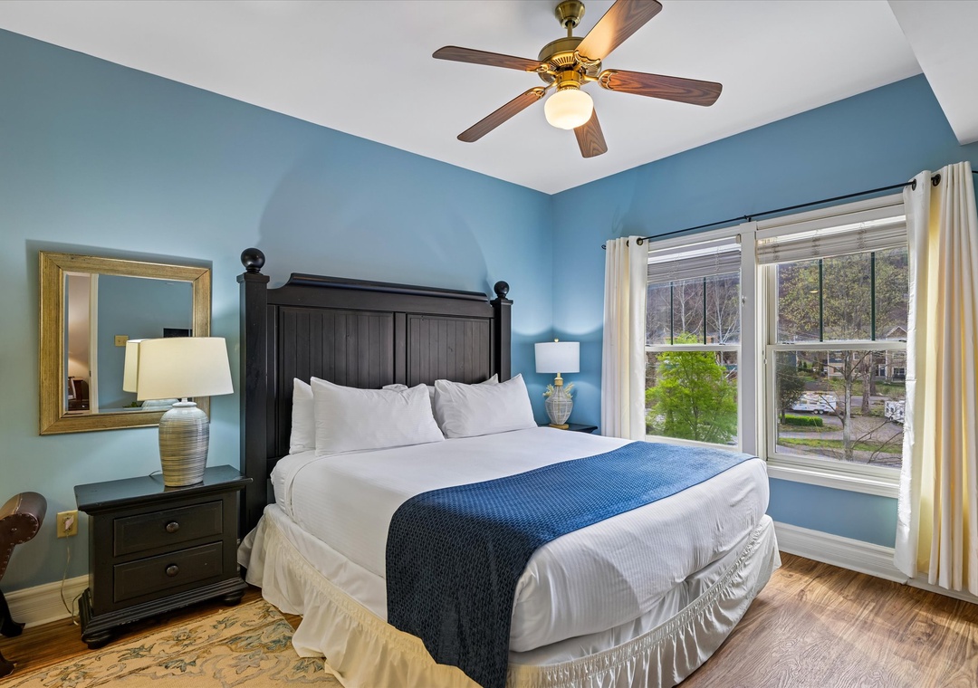 Sink into crisp white linens and let the gentle ceiling fan breeze lull you to sleep in this serene blue bedroom retreat.