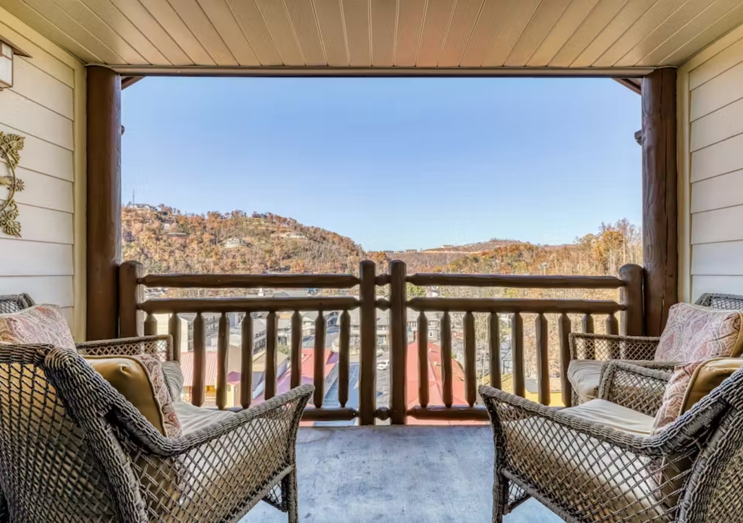 Relax in your private mountain retreat with wicker seating overlooking autumn hillsides and distant homes.