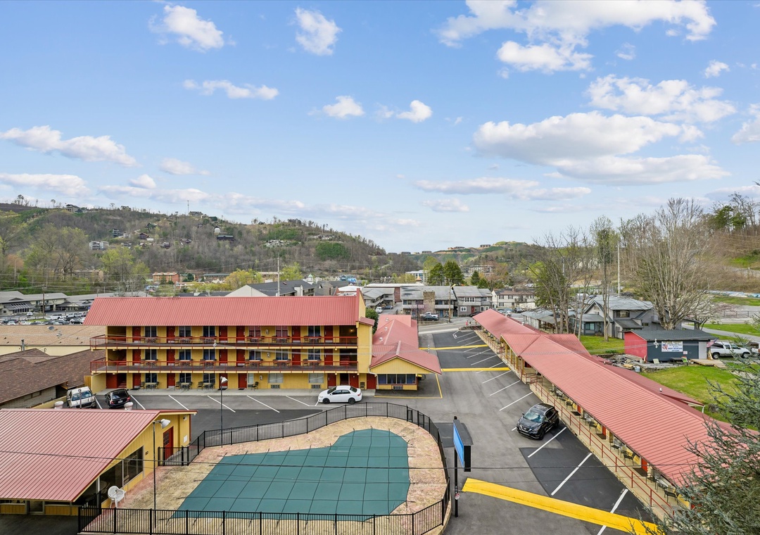 Aerial view of the property nestled in rolling hills, featuring convenient parking and pool facilities surrounded by peaceful mountain scenery.