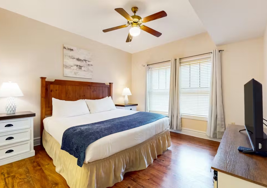 Relax in your peaceful bedroom featuring a cozy queen bed, ceiling fan for comfort, and TV for entertainment.