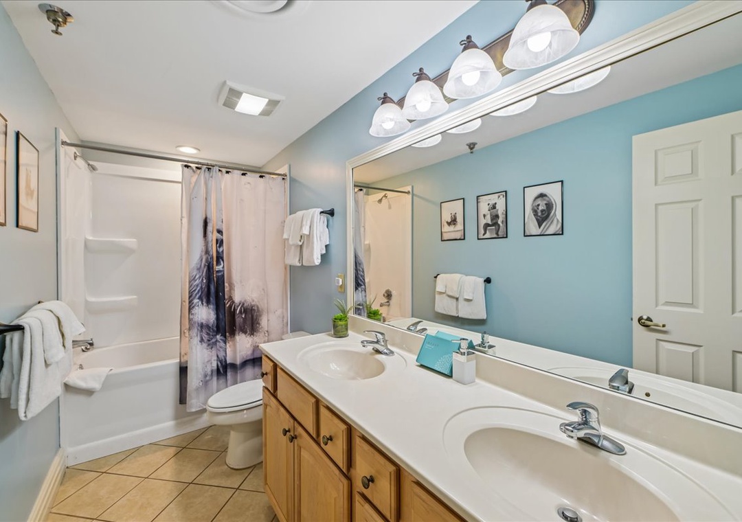 Refresh in your spacious bathroom featuring dual sinks, soothing blue walls, and a relaxing tub-shower combo—perfect for unwinding after your adventures.