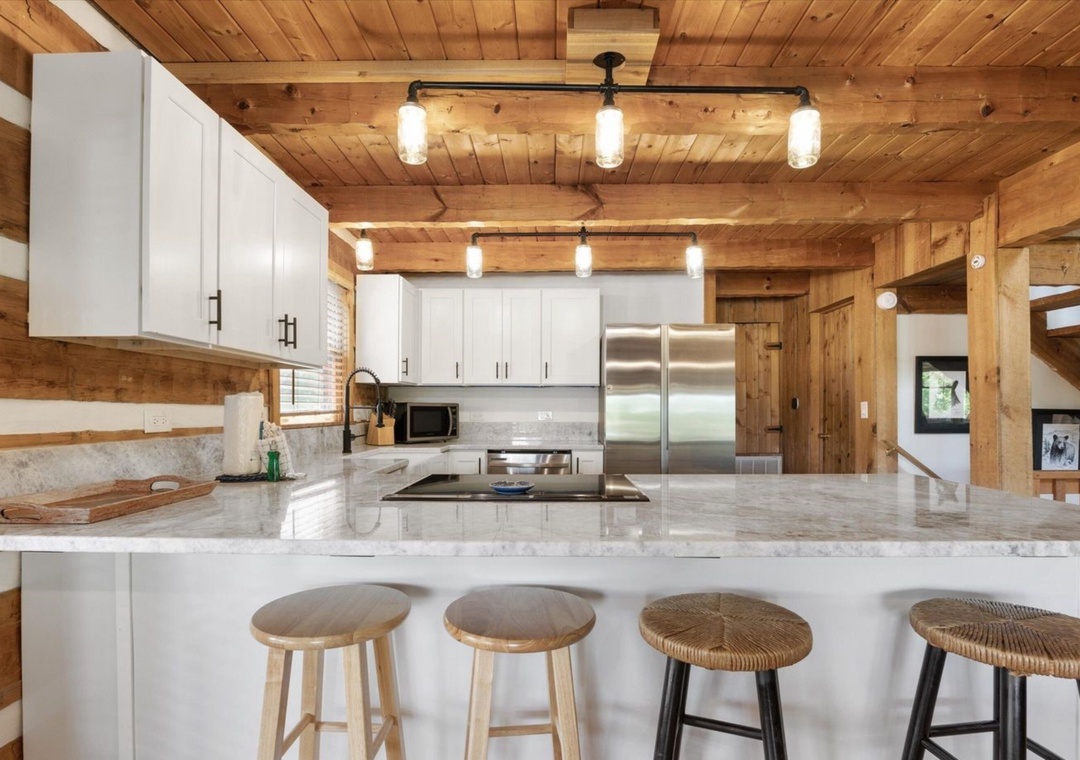 Your gourmet kitchen blends rustic charm with modern convenience—marble countertops, stainless appliances, and warm wood beams create the perfect cooking retreat.