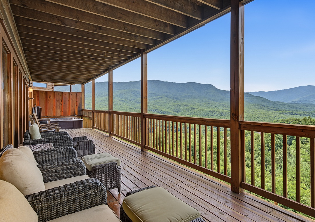 Covered deck offers lounging and a hot tub with stunning panoramic mountain and forest scenery stretching across the horizon.