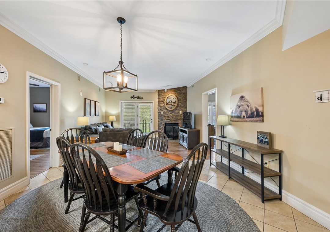 Your spacious dining area flows seamlessly into the living room, featuring rustic charm with a stone fireplace and cozy mountain decor.