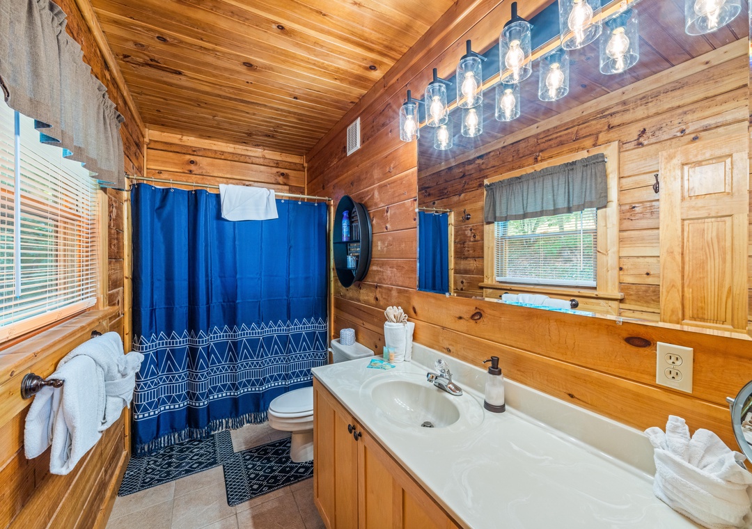 Step into your rustic-chic bathroom featuring warm wood walls, a sparkling chandelier, and fresh towels ready for your arrival. Refresh after a day of adventure in this cozy retreat.