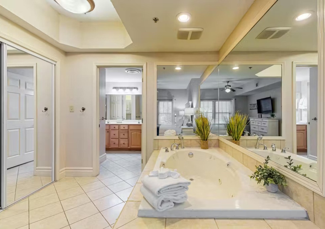 Sink into your private spa-like bathroom featuring a luxurious soaking tub surrounded by elegant mirrors and warm lighting for ultimate relaxation.