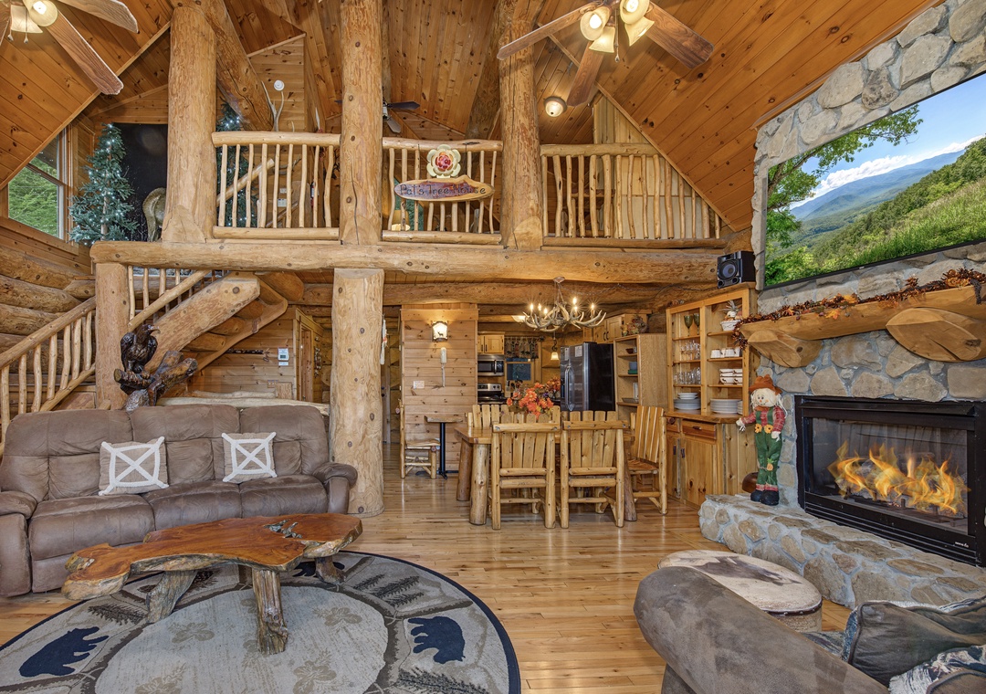 Relax in your spacious cabin featuring soaring log beam ceilings, a cozy stone fireplace, and rustic furnishings that blend comfort with mountain charm throughout the open living spaces.