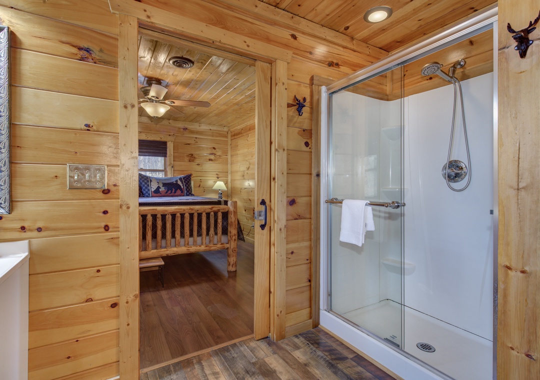 Step into your rustic cabin bathroom, where warm wood surrounds a spacious glass shower with mountain-inspired decor.
