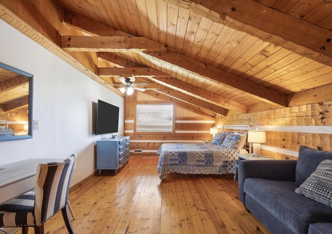 Cozy loft bedroom with exposed beams, warm wood surfaces, and comfortable seating for your mountain retreat.