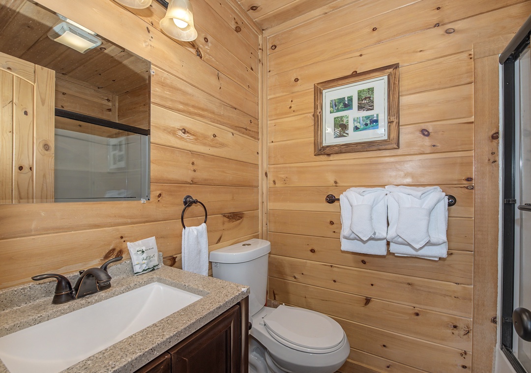 Unwind in your private bathroom with rustic wood-paneled charm, fresh towels, and a walk-in shower that feels like a cozy cabin retreat designed just for you.
