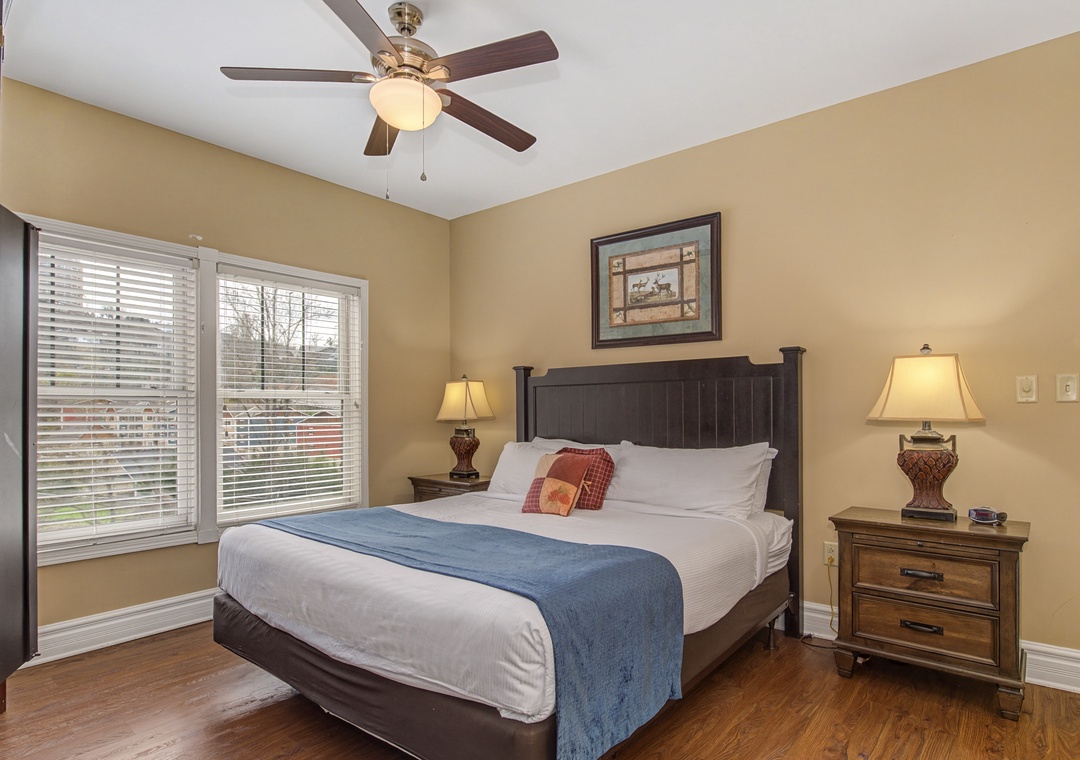 Sink into your comfortable bed with crisp linens and a cozy blue throw, while the ceiling fan keeps you cool.