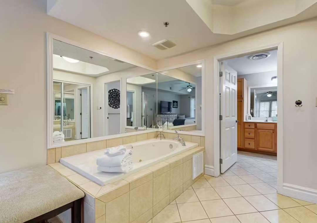Sink into your private jetted tub surrounded by warm tile and mirrors, creating the perfect spa-like retreat for ultimate relaxation.