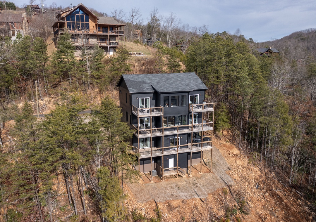 Modern mountain retreat nestled among rolling hills and forest, featuring multiple levels with private balconies throughout this scenic valley location.