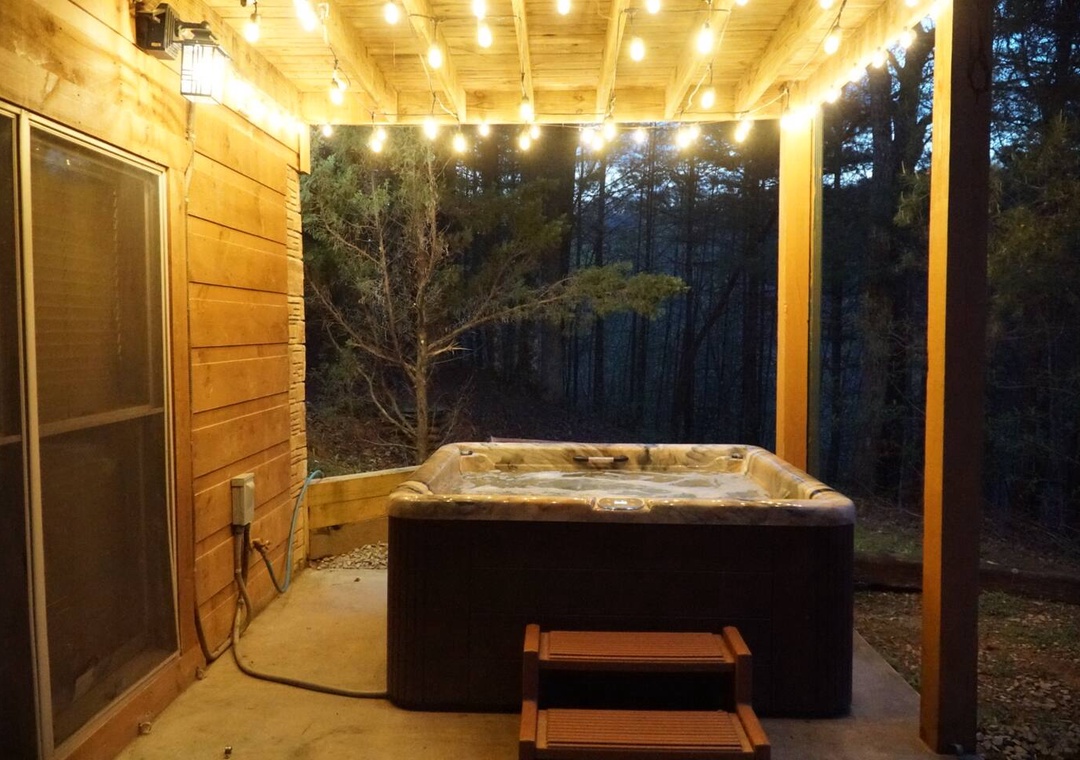 Soak under twinkling lights in your private hot tub, surrounded by peaceful forest views and warm wooden charm.