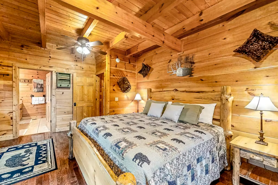 Drift off in your rustic log cabin bedroom, where exposed beams frame bear-themed bedding and cozy mountain decor surrounds you.