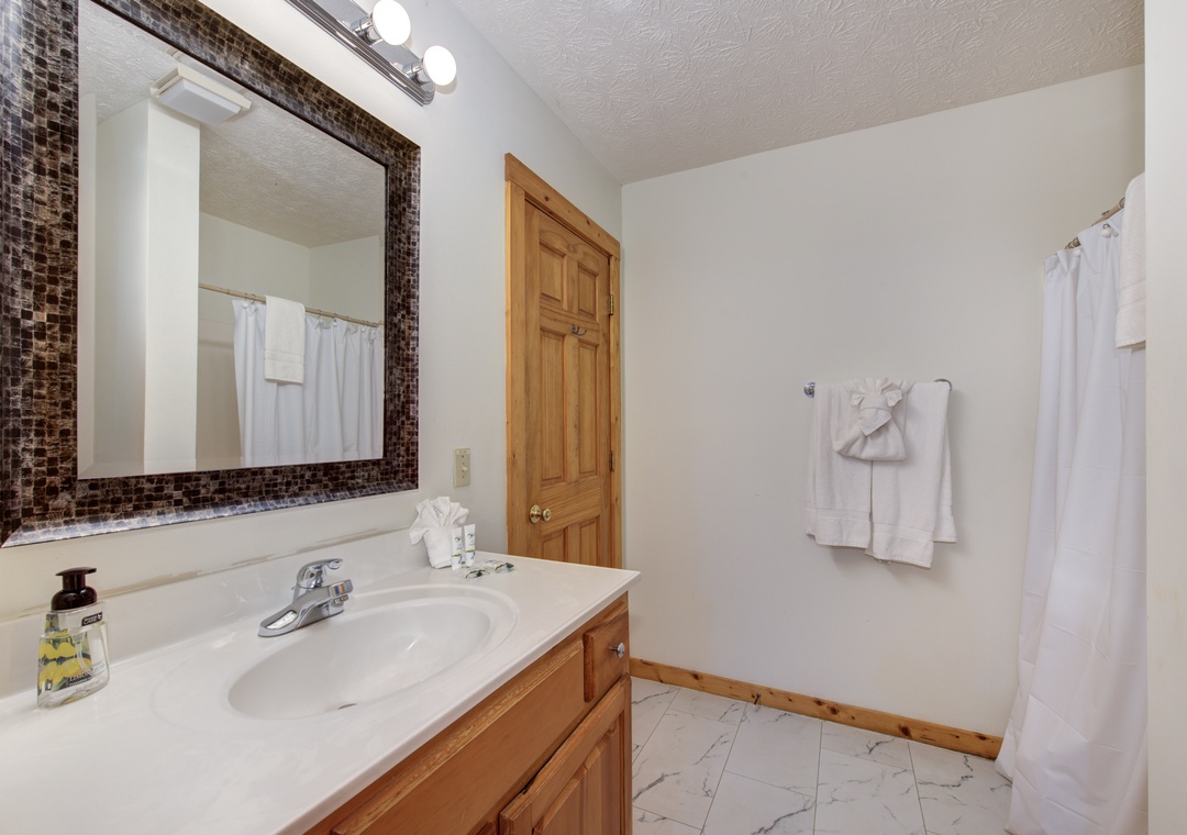 Refresh in your private bathroom featuring a mosaic-tiled mirror, marble floors, and plush white towels awaiting your arrival.