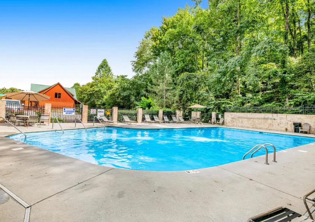 A spacious outdoor pool surrounded by lush greenery and mountain views. Plenty of lounge chairs and shaded seating let you relax poolside on sunny days.