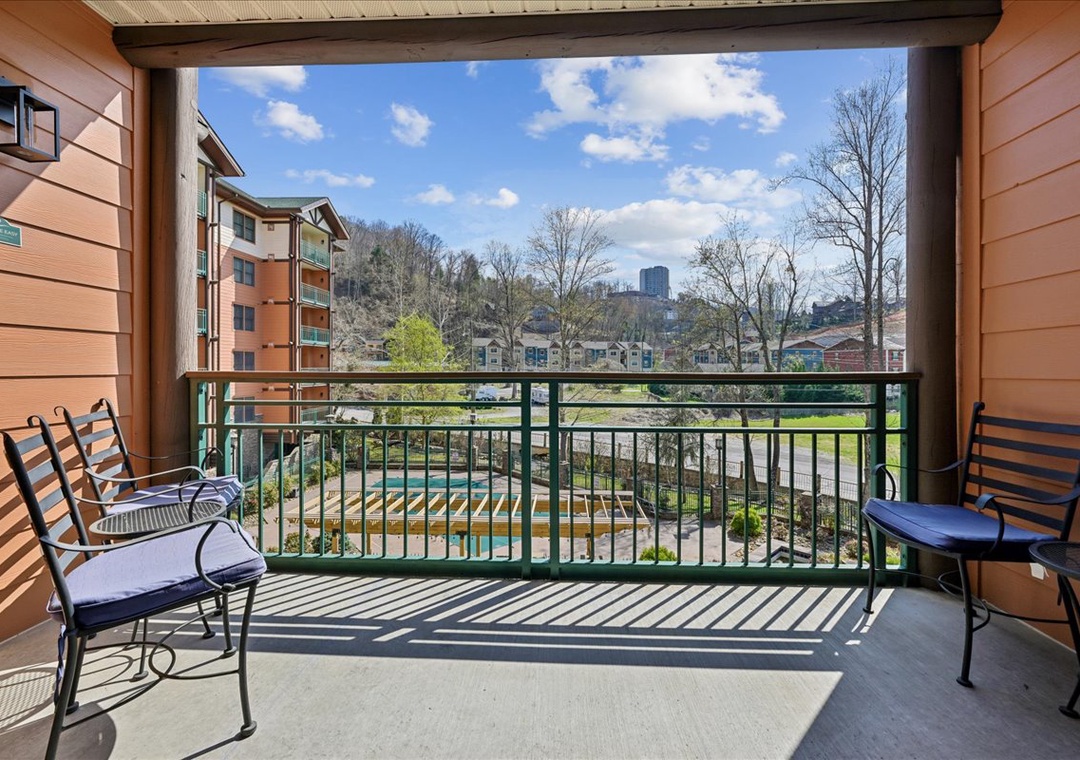 Enjoy morning coffee on your private balcony overlooking the sparkling pool and city skyline beyond.