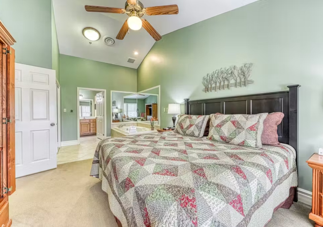 Relax in your spacious master suite with soothing green walls, plush quilted bedding, and an ensuite bathroom for ultimate comfort.