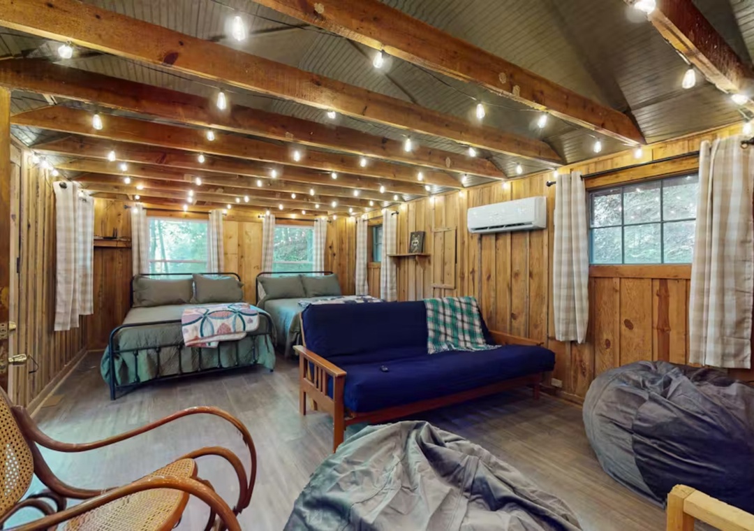 Unwind in your cozy cabin retreat with twinkling string lights, comfortable beds, and rustic charm perfect for your peaceful getaway.