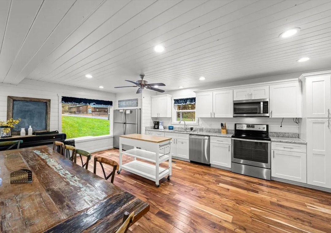 Your bright, open kitchen and dining space features modern stainless appliances, crisp white cabinetry, and warm hardwood floors—perfect for gathering with family or enjoying morning coffee at the farmhouse table.