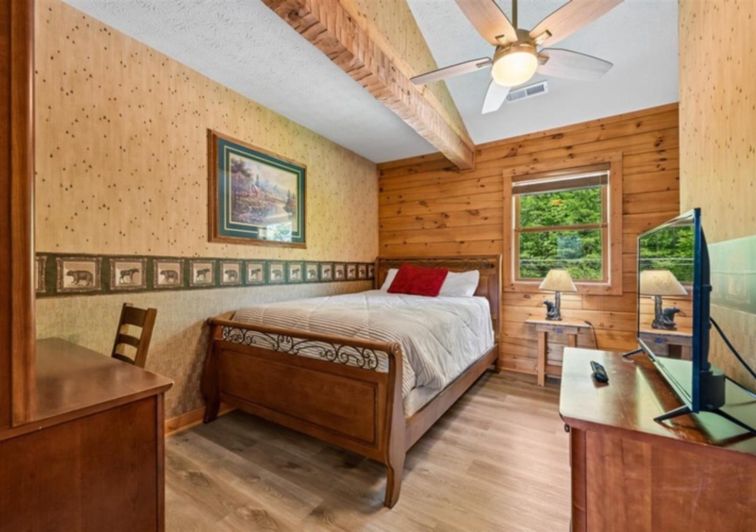 Your cozy bedroom blends rustic pine walls with charming decor, where exposed beams and woodland-themed accents create a cabin retreat. Wake refreshed under vaulted ceilings and gentle ceiling fan breezes.