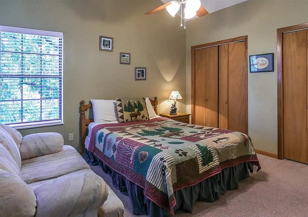 Your cozy bedroom features a plush queen bed with rustic charm, a comfy armchair for relaxing, ample closet space, and peaceful wooded views to start your mornings right.