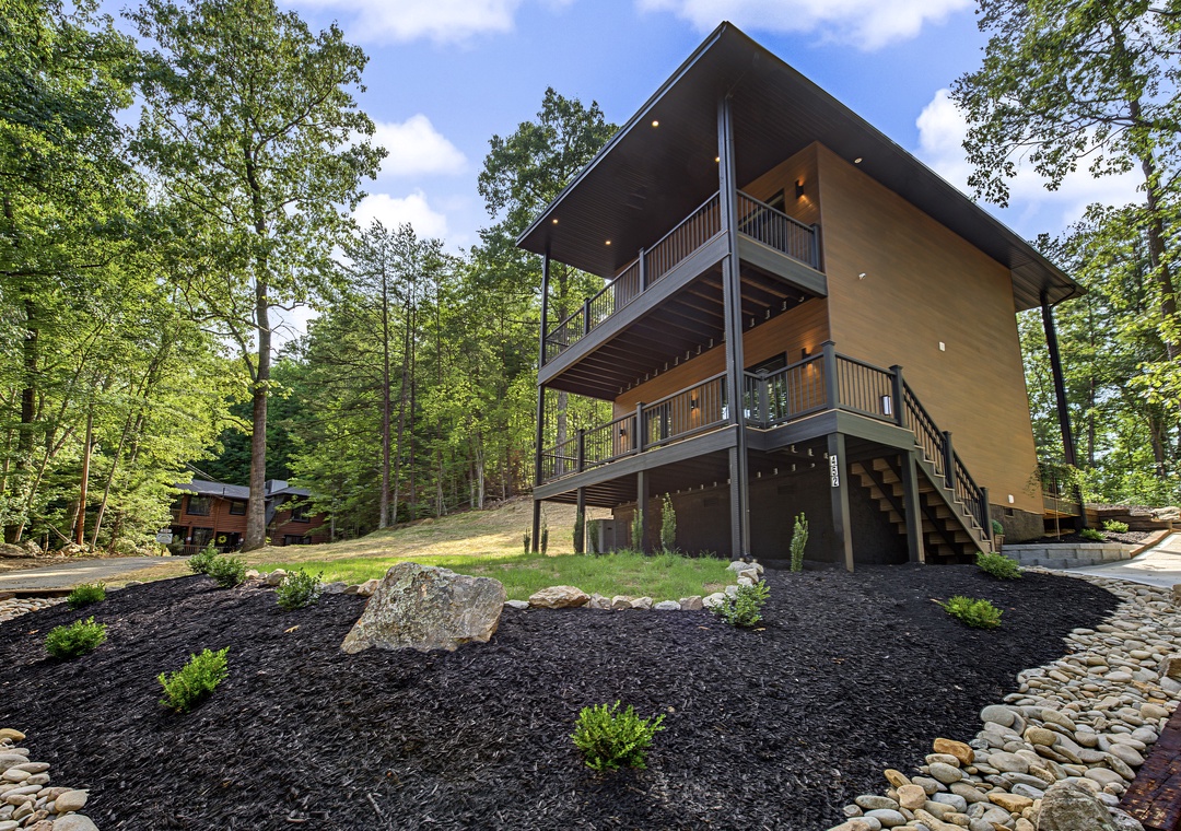 Modern architectural retreat nestled in a lush forest setting, featuring multi-level balconies and a welcoming exterior surrounded by native landscaping and mature trees.