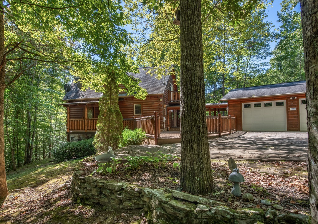A charming log cabin nestled among towering trees and lush greenery, offering a peaceful retreat with rustic charm and natural beauty surrounding the property.