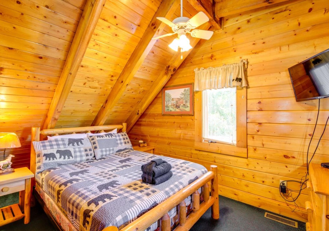 Drift off to sleep in your cozy log cabin loft, where rustic charm meets comfort under soaring timber beams and gentle ceiling fan breezes.
