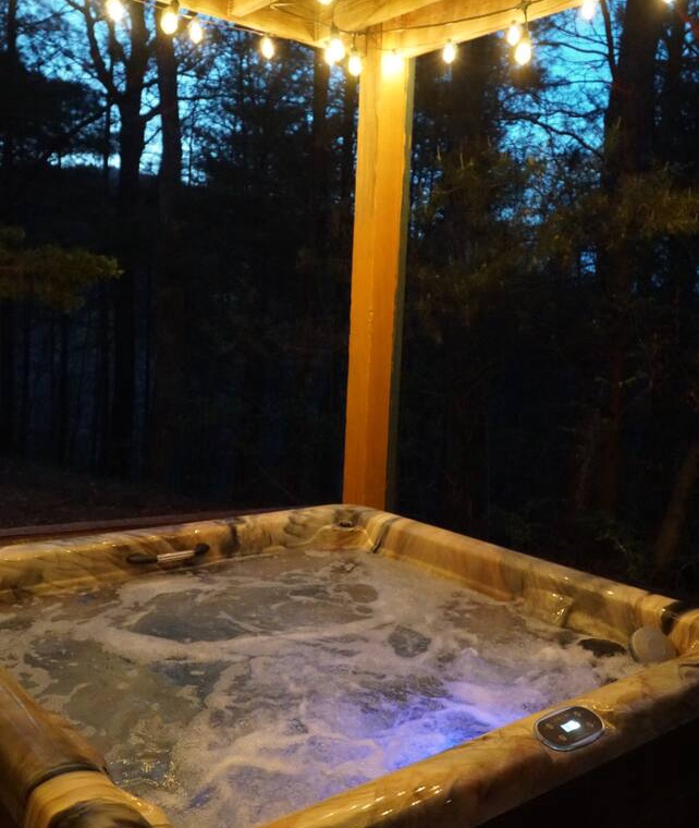Soak under twinkling lights in your private hot tub, surrounded by peaceful forest views for the perfect evening retreat.