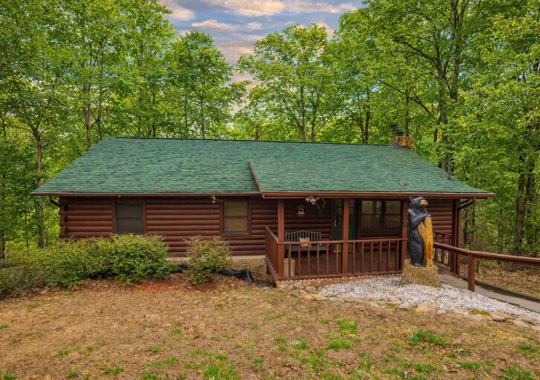 A charming log cabin nestled in a peaceful forest setting, featuring a welcoming covered porch and rustic charm surrounded by mature trees.