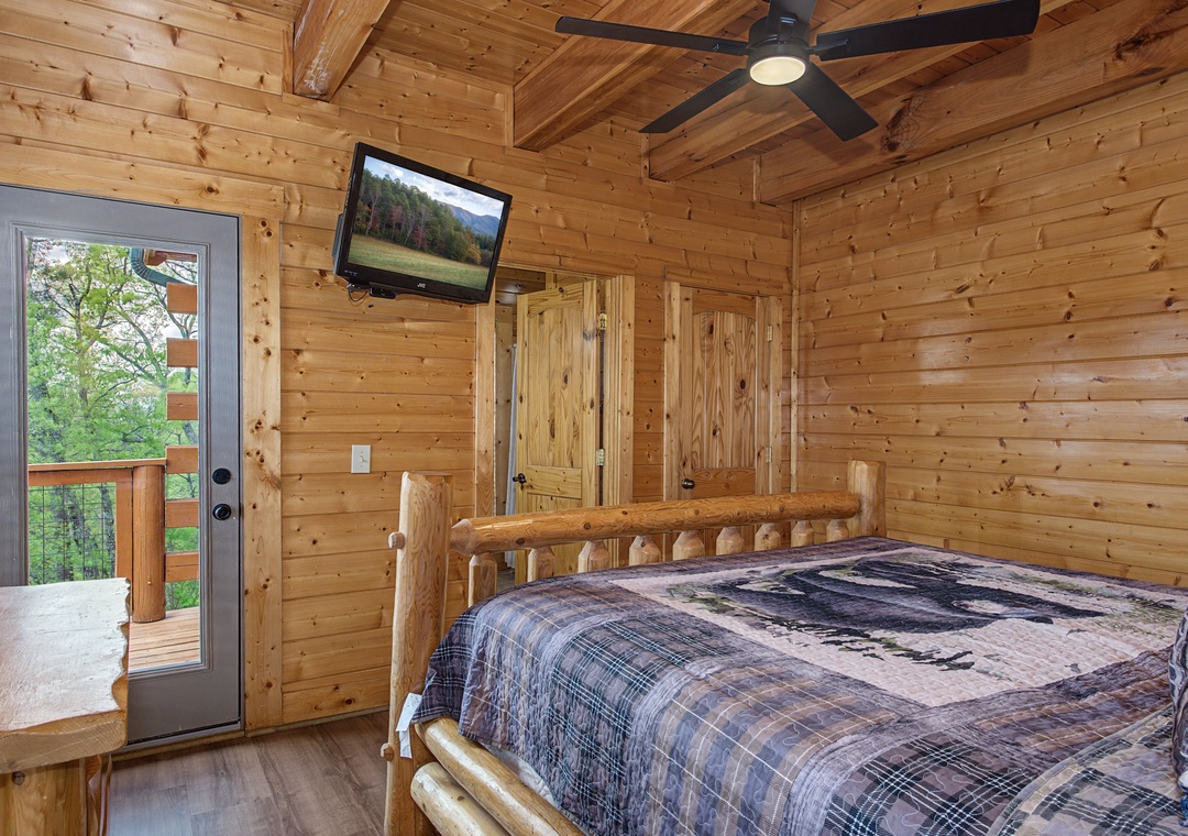 Unwind in your cozy log bedroom with rustic charm, ceiling fan comfort, and private deck access for peaceful moments.
