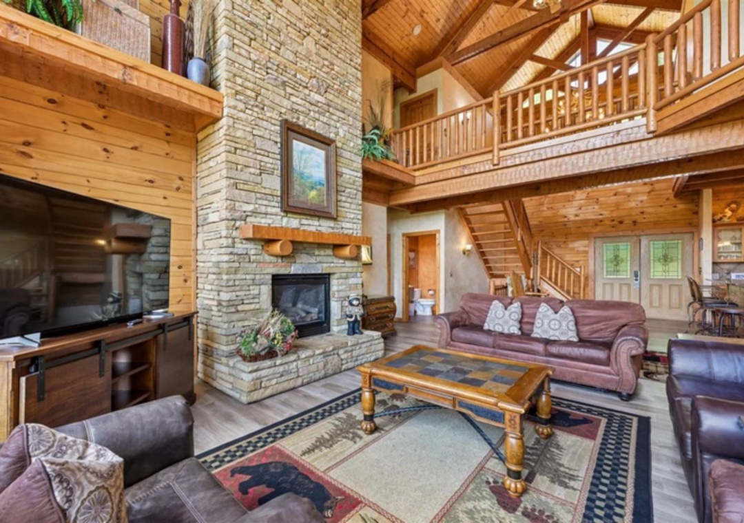 Unwind in your spacious living room with soaring ceilings, warm wood beams, and a cozy stone fireplace that makes every moment feel like home.
