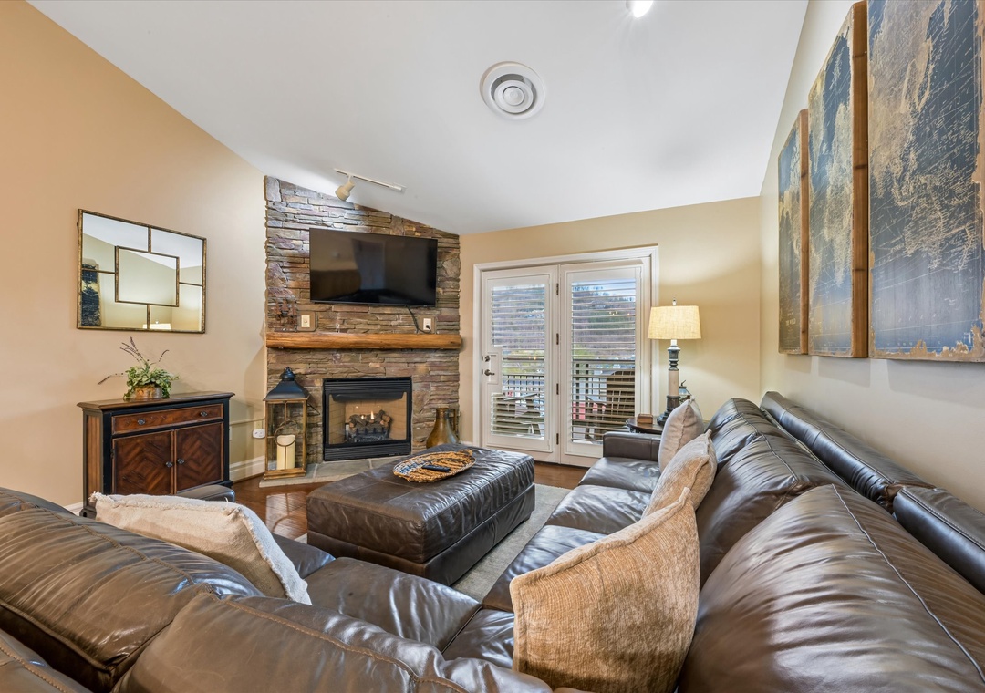 Unwind in your cozy living room with plush leather seating, crackling fireplace, and stunning mountain views through French doors.