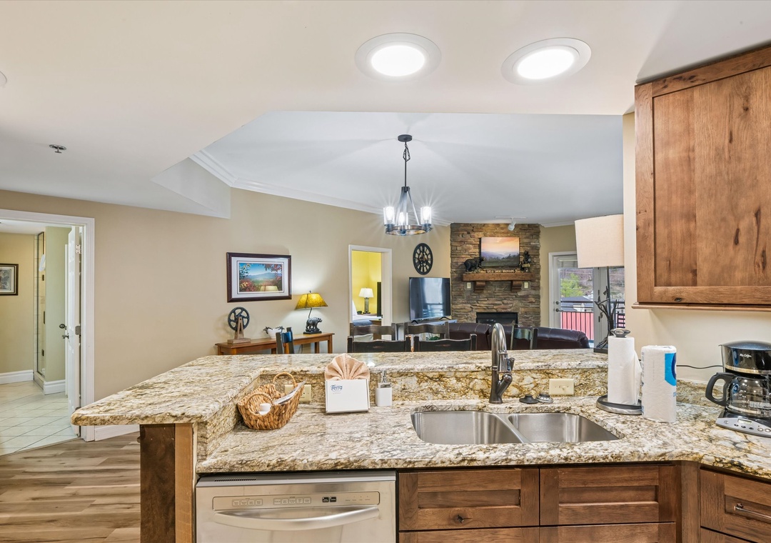 Your spacious kitchen features granite countertops and warm wood cabinets, flowing seamlessly into the cozy living area with stone fireplace.