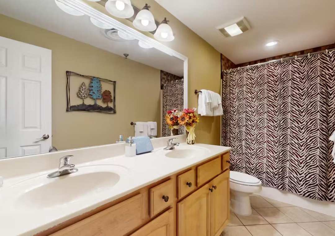 Refresh in your stylish bathroom featuring dual sinks, elegant patterned wallpaper, and thoughtful touches that make your stay feel like home.